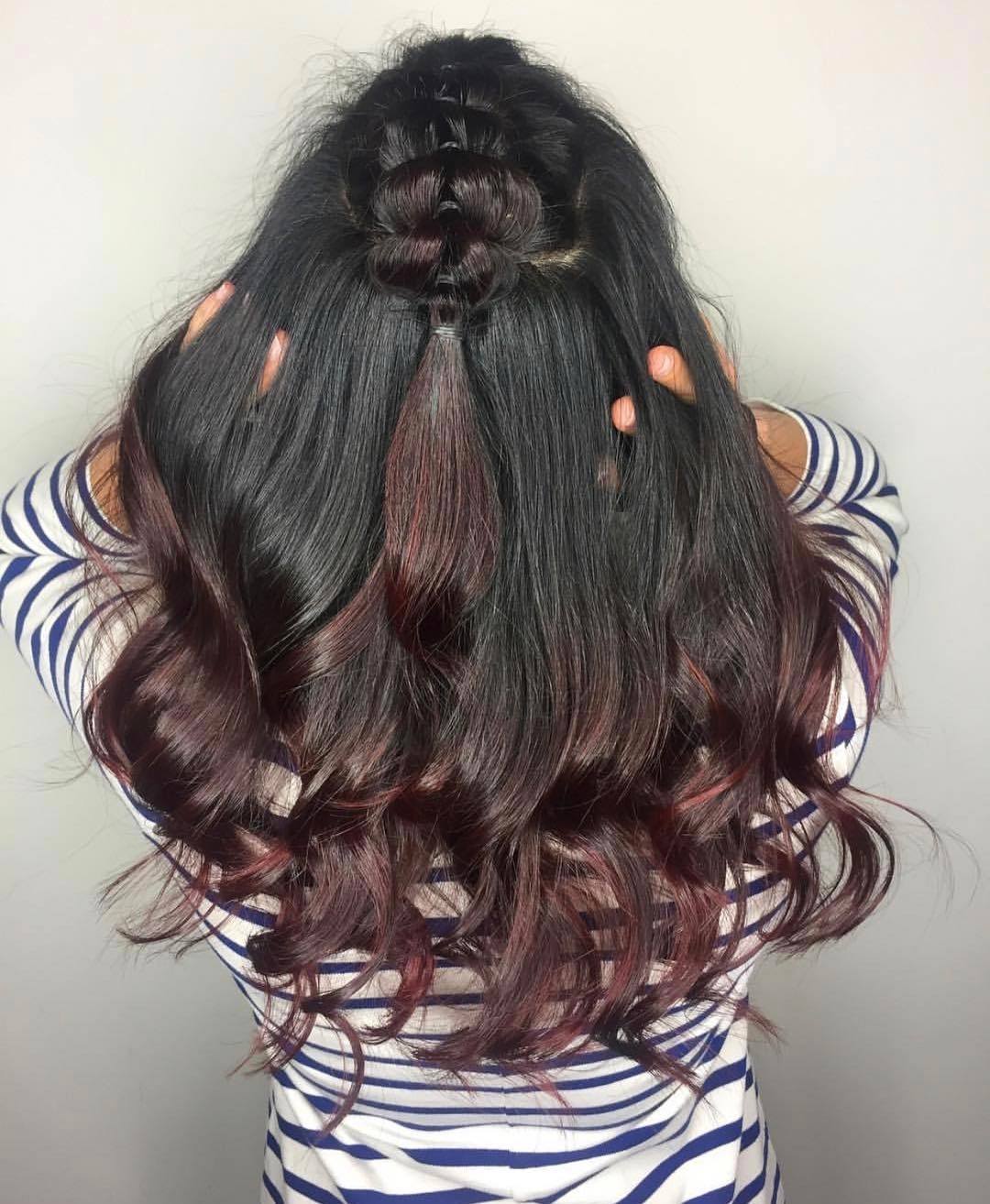 Woman with long curly black to mahogany ombre hair in a half-up pull-through braid