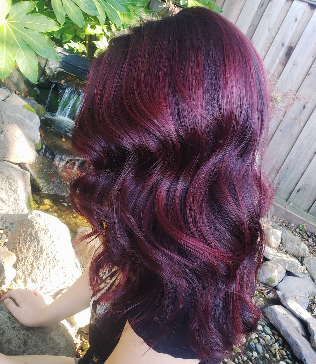 Woman with mid-length curly burgundy mahogany hair